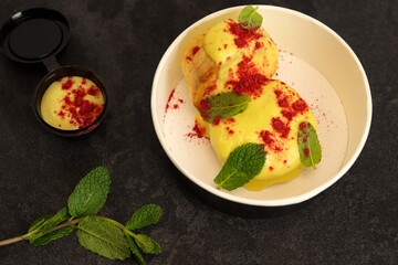Cottage cheese casserole or pudding served with mango puree cream and mint in eco paper box. Healthy breakfast food, sweet snack or meal rich in Protein, Calcium. Restaurant dish delivery concept. 
