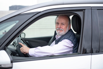 portrait of an elderly driver in car or taxi