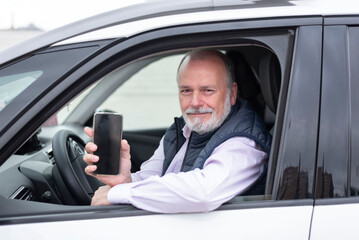 portrait of an elderly driver in a car or cab with mobile phone