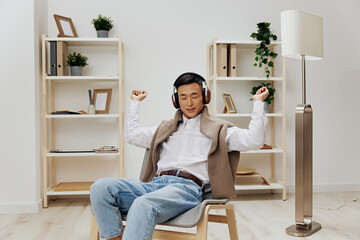 Asian man sweater on the shoulders headphones music sitting in the room technologies