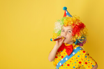 Funny kid clown against yellow background. Happy child playing with festive decor. Birthday and 1...