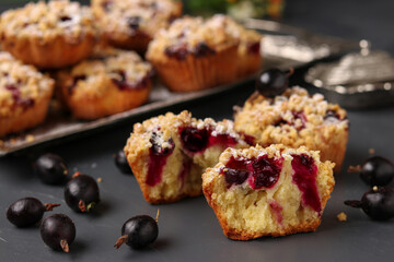 Homemade muffins with berries and streusel, sprinkled with powdered sugar on a dark gray background.