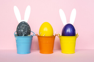 multi colors painted easter eggs in colored buckets with rabbit ears. Happy Easter Card	
