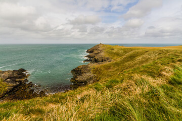 Grassy headland or peninsula with coastguard lookout in distance.