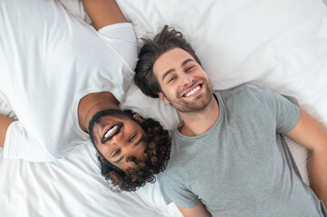 Happy gay couple posing for the camera in bed