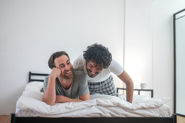 Happy gay couple lying on the duvet