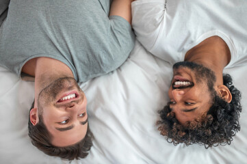 Happy gay couple lying in the bedroom