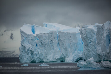 Ein anmutiger Eisberg mit hohen Eistürmen, blau weißem Eis und riesigen Eishöhlen in der...
