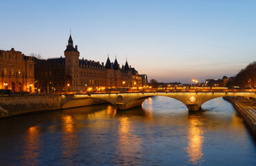 Panorama of Conciergerie and Illuminated bridge Pont au Change at night, Paris.