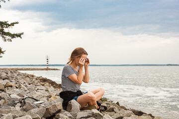 Beautiful girl on the sea overlooking the lighthouse and blue sky with clouds