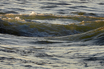 Sea waves at sunset. Sun glare in the waves.