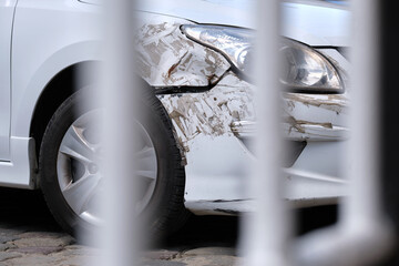 Dented car with damaged fender parked on city street side. Road safety and vehicle insurance concept