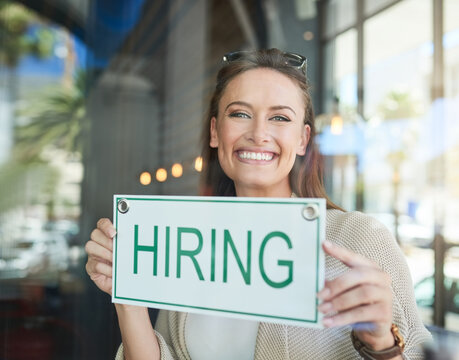 Were Hiring. Portrait Of A Young Entrepreneur Holding A Hiring Sign In Her Business.