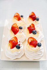 strawberries, blueberries and cream decorates to Anna Pavlova cakes.