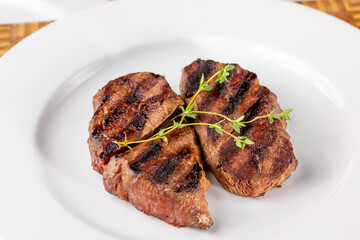 Grilled marbled beef steak lies on a white plate