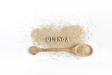 Whole grain quinoa on a white background, accompanied by a wooden spoon and letters.