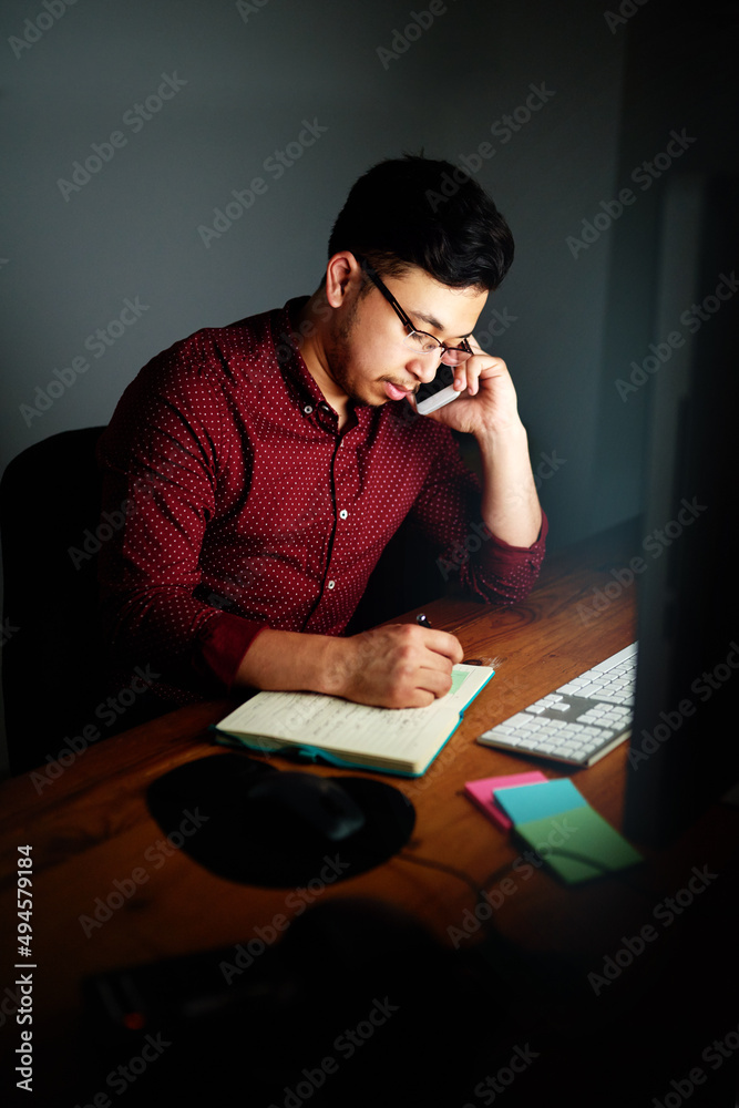 Aufkleber putting in those overtime hours. shot of a young male designer talking on the phone and taking notes