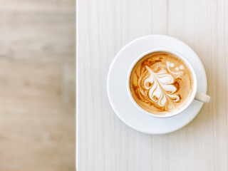 Top view  of fresh cappuccino coffee in white ceramic cup with copy space.