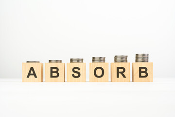 absorb - text written on wooden block with stacked coins on white background, growing trend