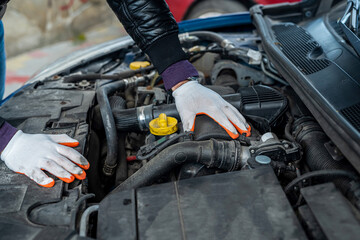 a professional good mechanic in special gloves diagnoses the car.