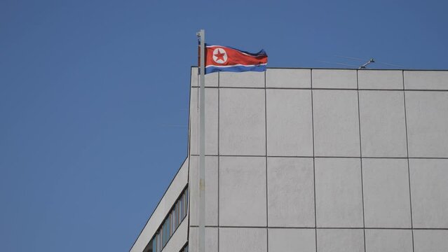 The flag of North Korea in front of a building. 