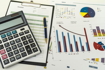 Financial paper charts with calculatop and pen on office desk