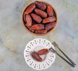 Bowl of dates fruit on colorful marble background, top view