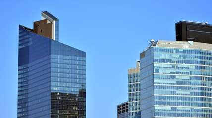 Obraz premium Minimalist glass facade, steel framework holding the large transparent panels. Contemporary commercial architecture, vertical converging geometric lines. Blue sky reflection in the glass panels