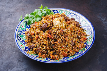 Traditional Uzbek fergana plov with devsira rice and lamb meat served as close-up on a handmade painted lagan platter