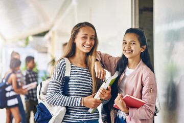 Best friends and study buddies. Portrait of two happy schoolgirls standing together in the hallway...