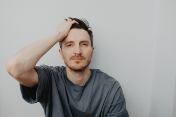 Handsome young man over grey wall with serious expression on face. Simple natural looking at camera.