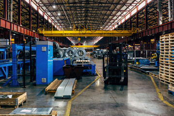 Metalworking factory production line. Rolls of steel and metal profiled parts in workshop