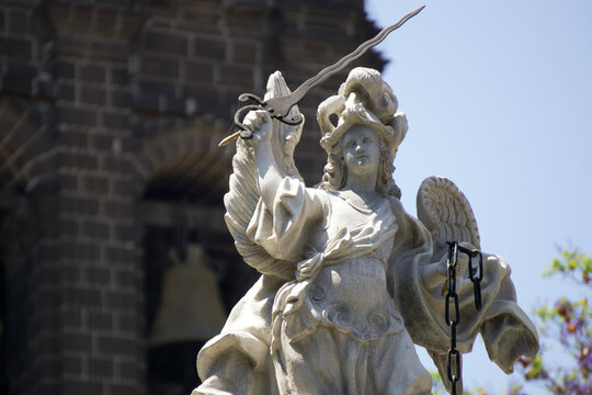 Statue of the Archangel Saint Michael that crowns the fountain of the same name in the Zócalo or main square of Puebla, Mexico. Behind him you can see the Catholic Cathedral of Puebla.