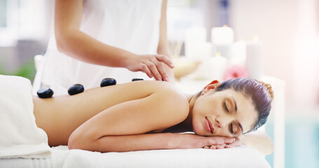 Its a place to restore balance. Shot of a young woman getting a hot stone massage at a spa.