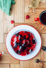 Cake with berry jelly with blueberries and raspberries on a wooden table