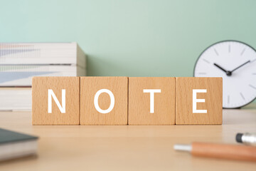 「NOTE」と書かれた積み木ブロックが置かれたデスク