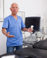 Portrait of mature male sonographer doctor in uniform in medical diagnostics office