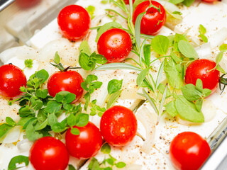 Obraz na płótnie Canvas Greek feta cheese, fresh cherry tomatoes, onions and mediterranean herbs are prepared to be cooked in the oven. 