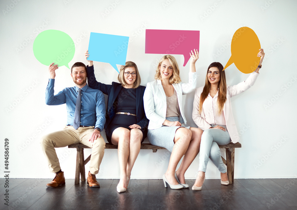 Poster say what you need to say. shot of a group of work colleagues seated next to each other while holding