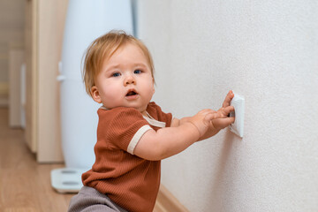 Children's curiosity is a danger to life -  baby girl touching a socket. .