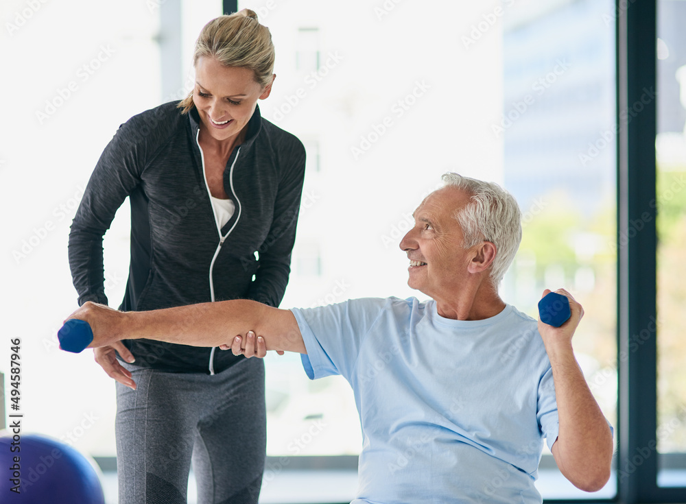 Sticker Shes such a friendly professional. Cropped shot of a happy senior man working out with weights with the help of a physiotherapist.