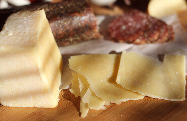 Peppercorn Salami on Tray With English and Irish Cheese, Sliced Apples and Spices in Rustic Kitchen