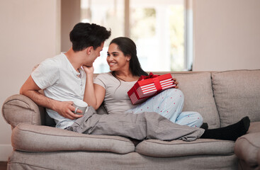 Thank you so much. Full length shot of an affectionate young woman thanking her boyfriend for her gift on the living room sofa.