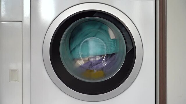 Colorful laundry inside a front loader washing machine spinning counter clockwise