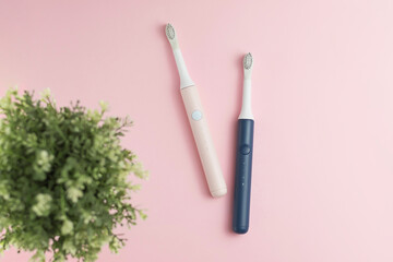 New modern ultrasonic toothbrushes. Dental care supplies with green leaves on pink pastel background. Oral hygiene, gum health, healthy teeth. Dental products Ultrasonic vibration toothbrush.