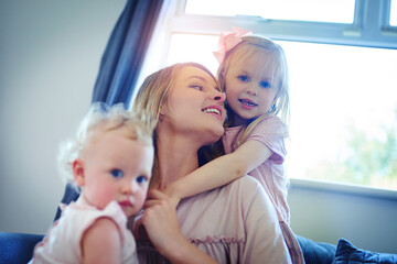 Family, the ultimate source of happiness. Shot of two adorable sisters bonding with their mother at home.