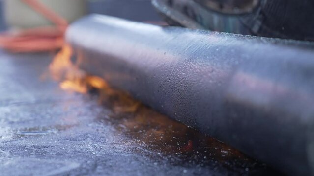Roofer is welding the roofing felt with fire on a flat roof