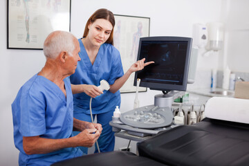 Portrait of young positive friendly technician showing new ultrasound scan to doctor in clinic