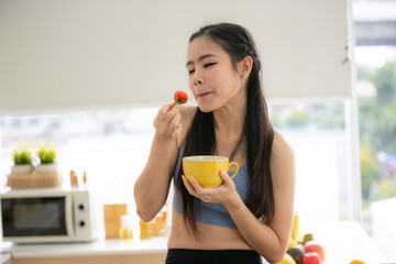 young Asian woman cooking vegetable healthy food and eating or drinking in home kitchen