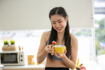 young Asian woman cooking vegetable healthy food and eating or drinking in home kitchen